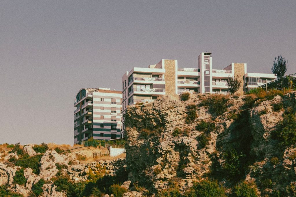 A modern apartment complex perched on a scenic rocky cliff under a clear sky.